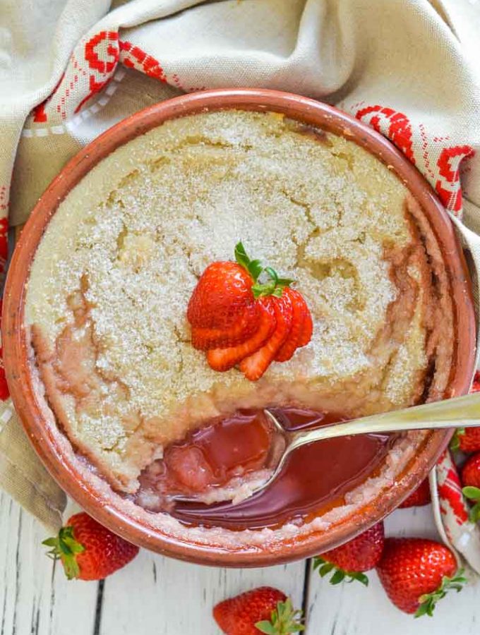 baked strawberry semolina pudding with piece cut out and spoon resting in bowl