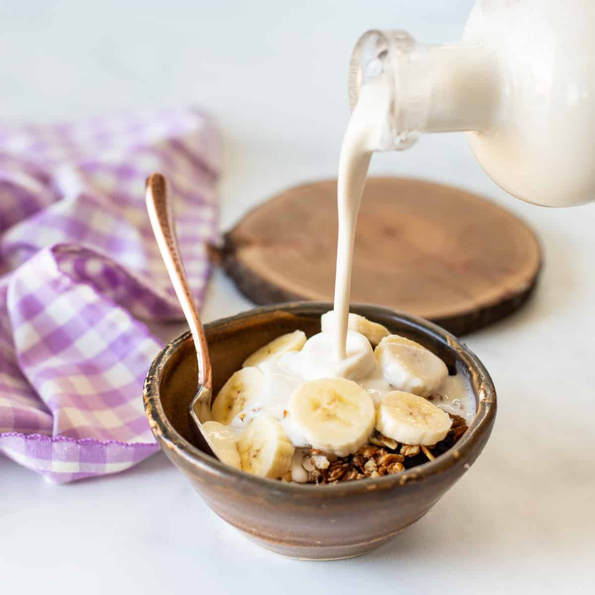 cashew milk pouring over some breakfast cereal in a bowl