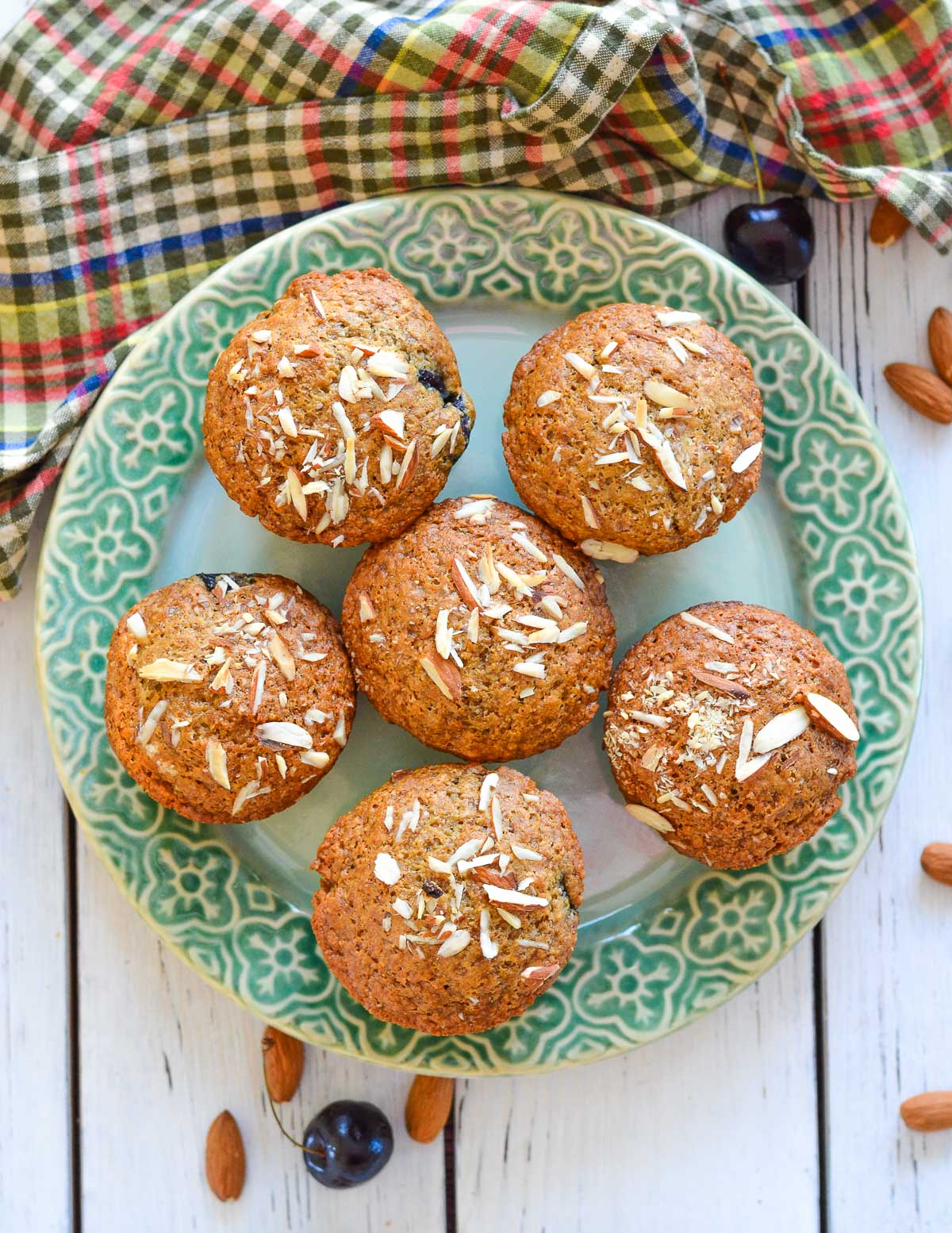 a green plate with cherry almond muffins on it