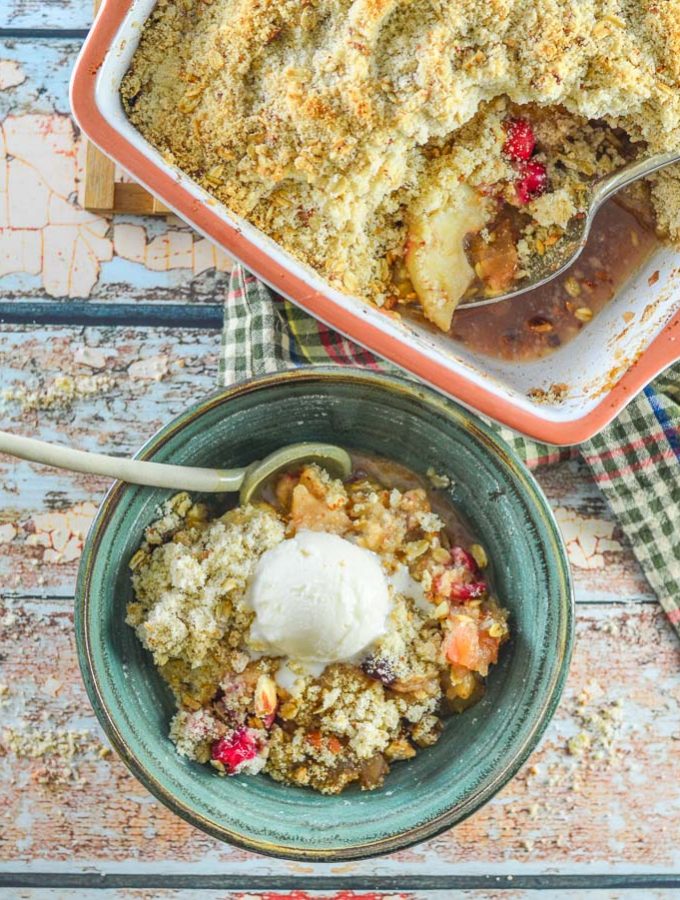 Overhead shot of Cranberry Apple Pear Vegan Crumble served up in a bowl with casserole full of crumble next to it