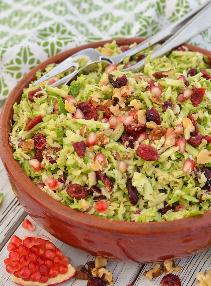 Close up shot of Cranberry Pecan Brussels Sprout Salad with pomegranate arils in foreground