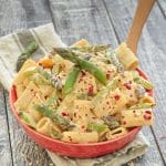 Creamy Asparagus Lemon Pasta Salad in a red bowl on a rustic wood backdrop