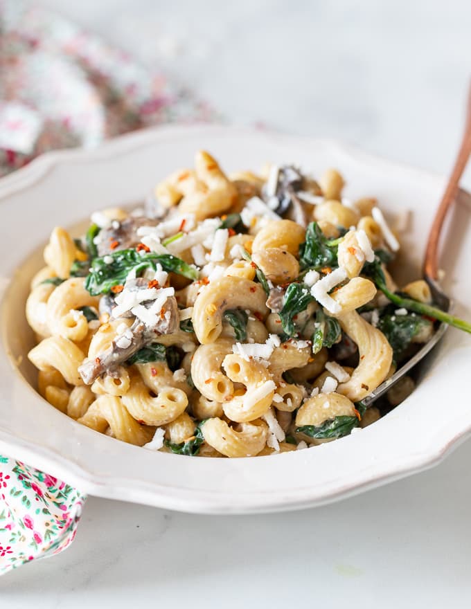 creamy vegan mushroom pasta in a bowl and sprinkled with vegan cheese shreds 