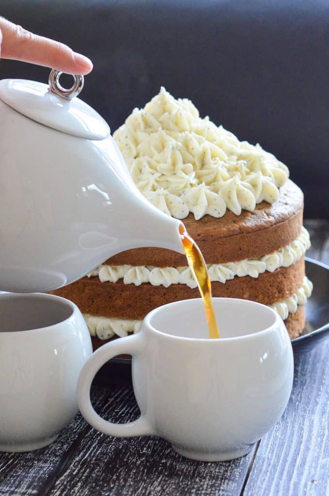 Vegan Earl Grey Cake in background with a cup of tea being poured in foreground