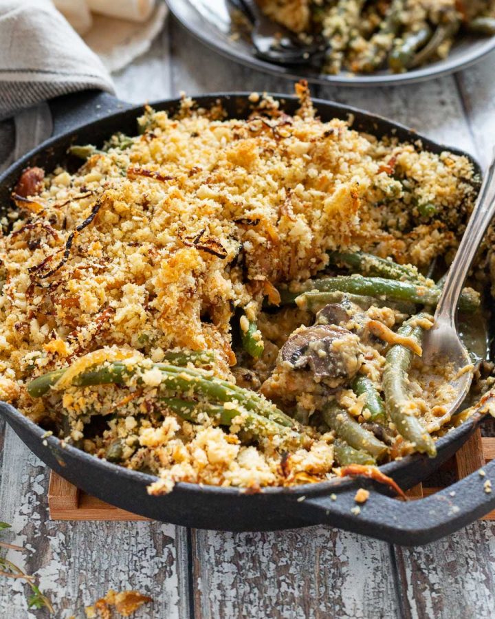 a skillet full of green bean casserole with a spoon in it