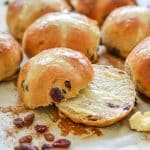 a sliced and buttered vegan hot cross bun