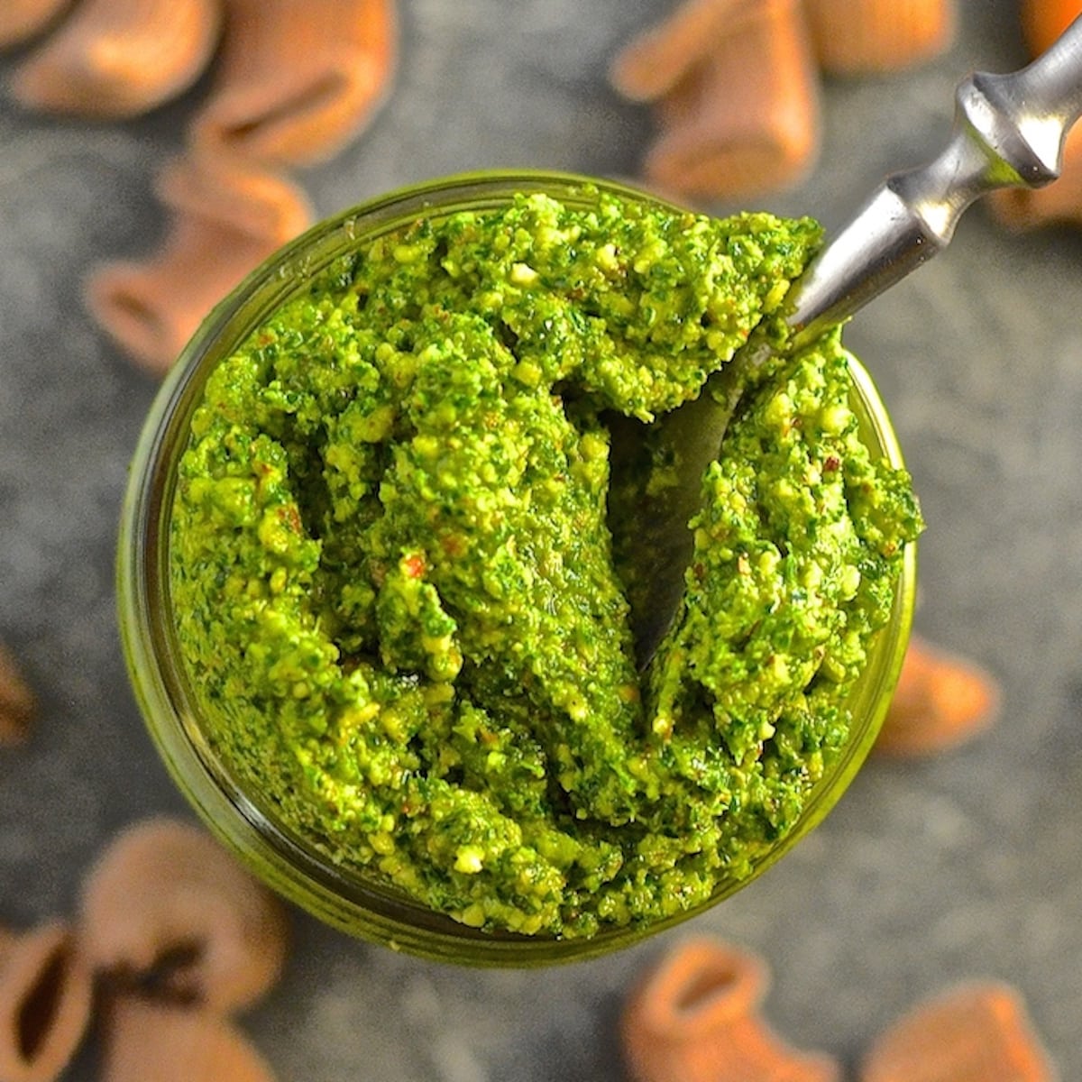 a jar of kale almond pesto with a spoon in it. Photo taken from above.