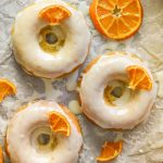 3 frosted, sticky, orange olive oil baked donuts with candied orange pieces