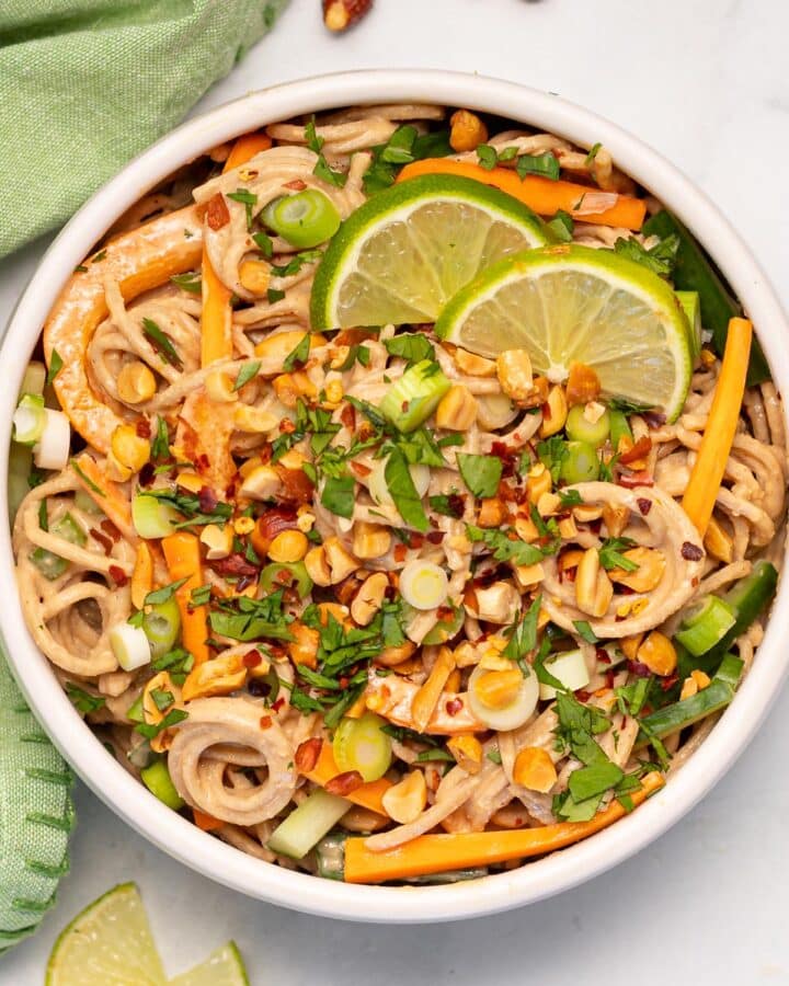 a bowl of peanut noodles with fresh vegetables and cilantro