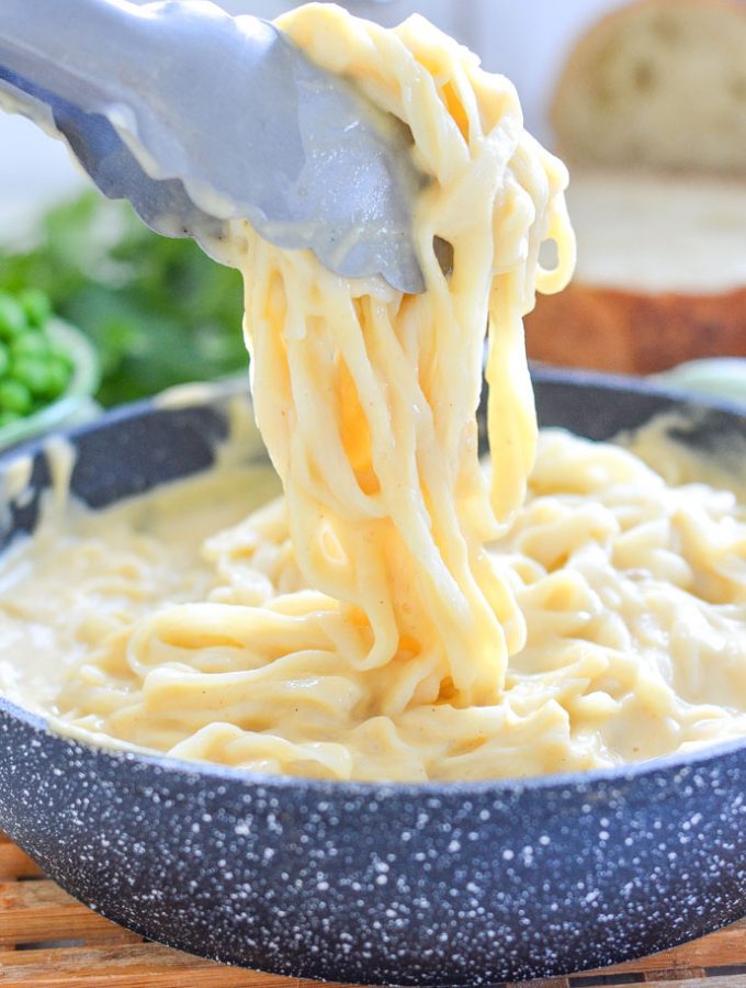 Skinny Fettuccine Cauliflower Alfredo in a pan with tongs lifting some out