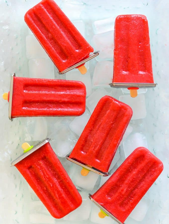 strawberry popsicles laid out on ice cubes