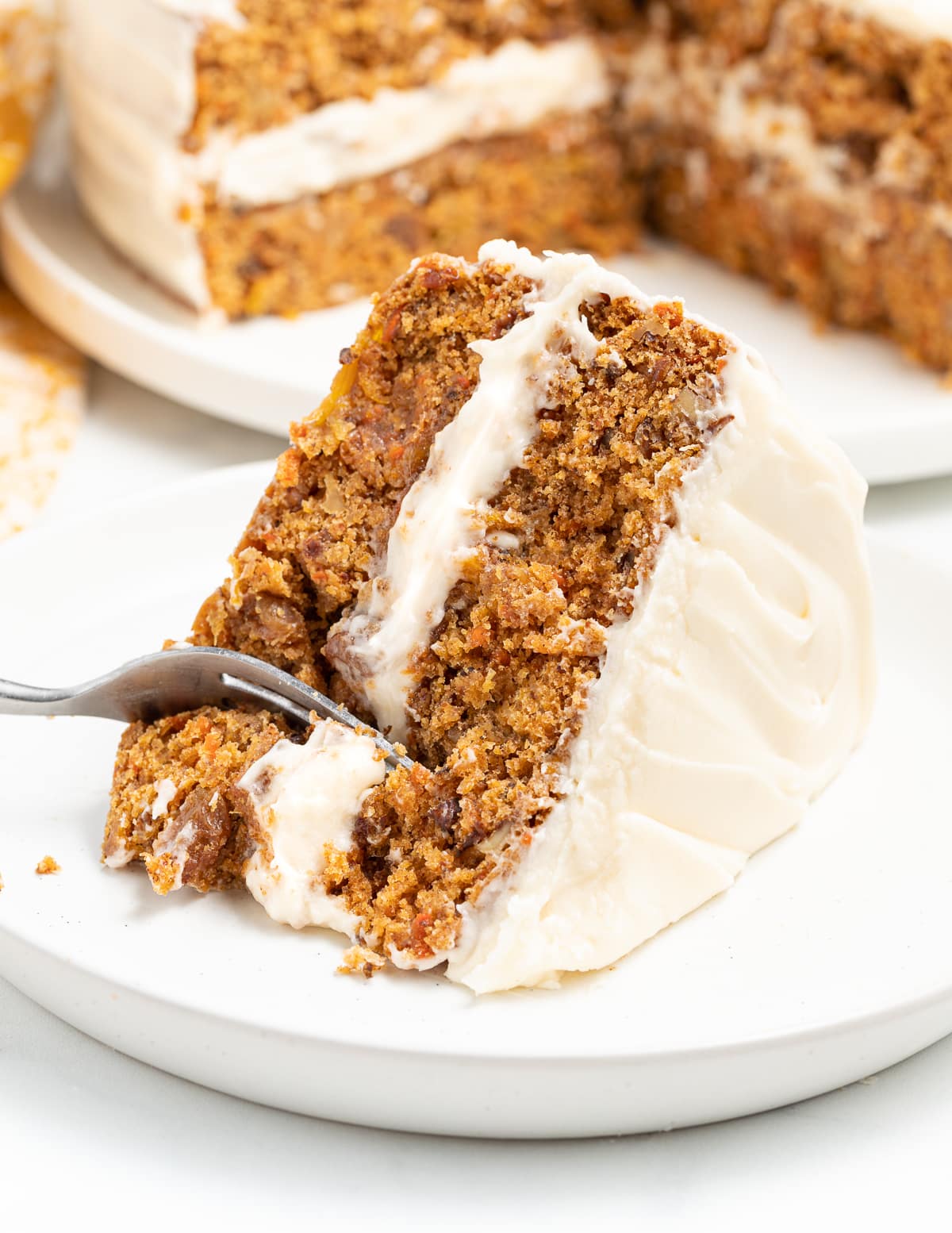 a fork taking a piece out of a slice of carrot cake