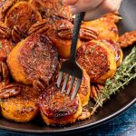 a fork being stuck into a pile of caramelized sweet potatoes